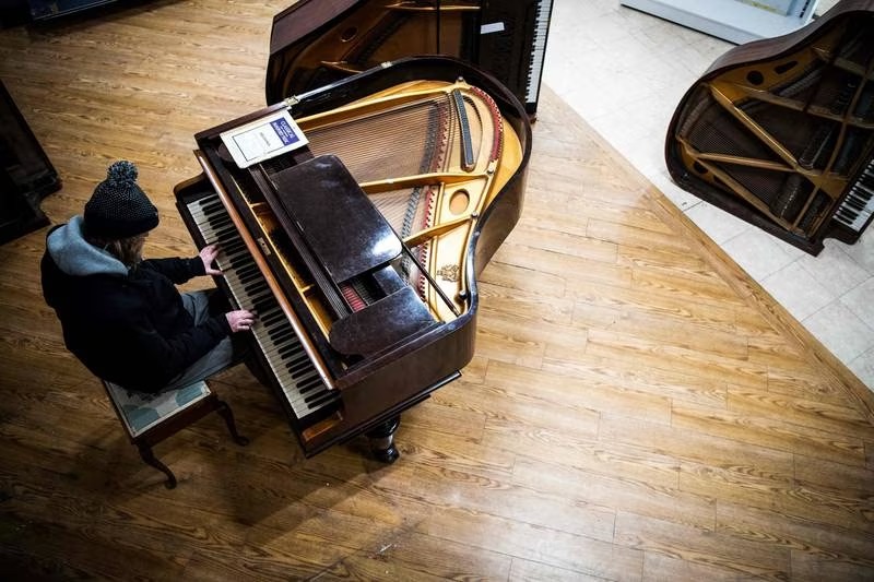 A customer tries a piano at the Pianodrome, a centre aiming to refurbish and repair pianos in Edinburgh, Scotland. Photo: AFP